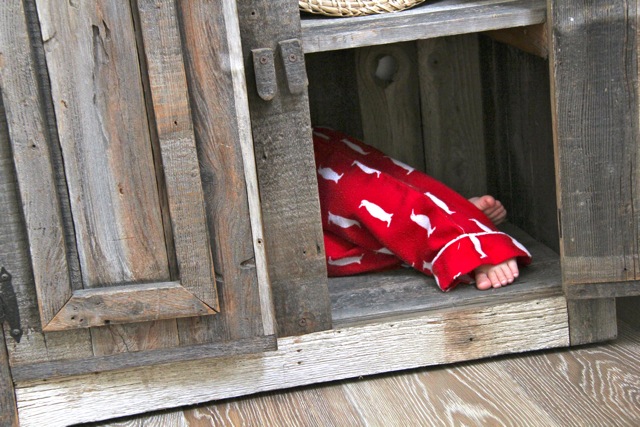 toddler feet sticking out of rustic barn wood baker's rack