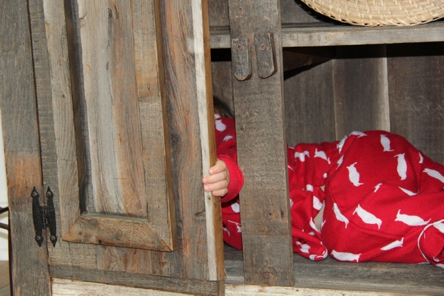 toddler feet sticking out of rustic barn wood baker's rack