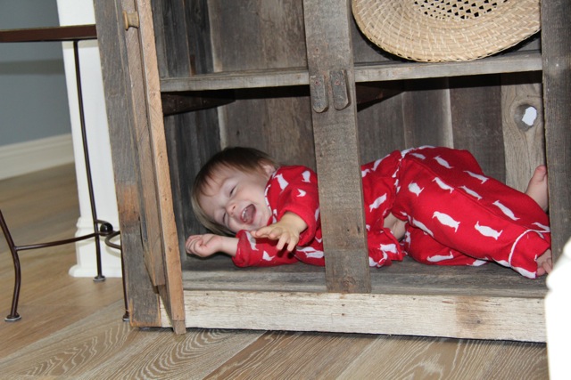 laughing toddler hiding in furniture