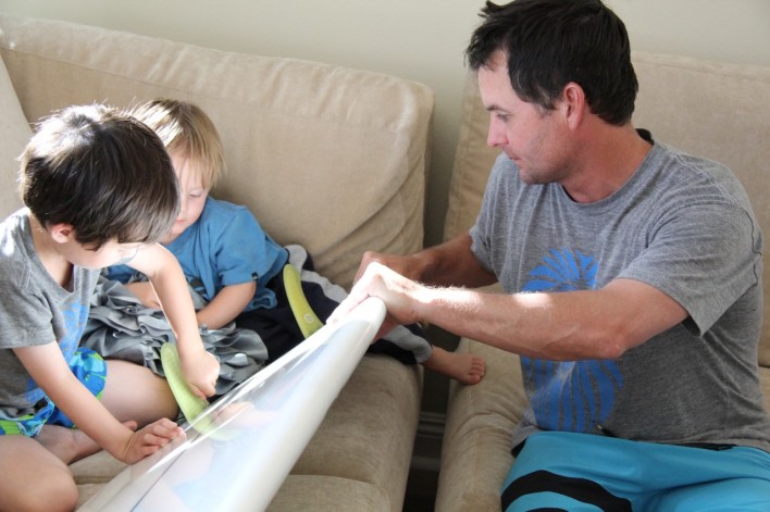 boys putting fins on a new surfboard