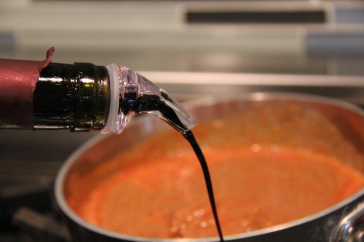 pouring balsamic vinegar into pasta sauce