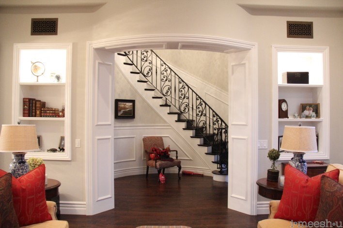 view of gorgeous sweeping wrought iron stairwell, white wainscoting panels