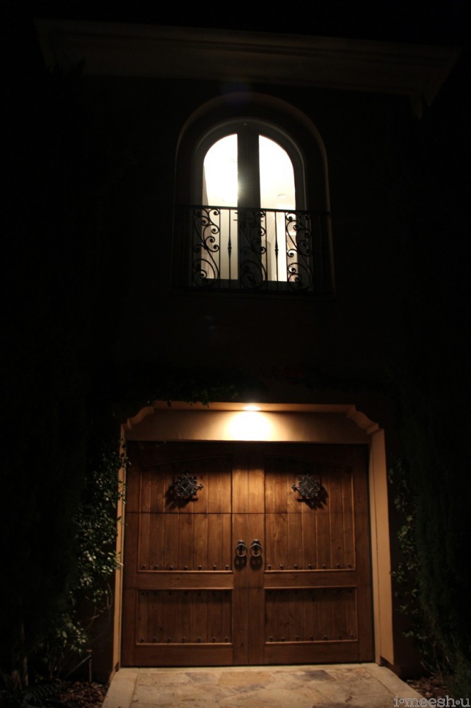 arched window backlit above dark wood garage door